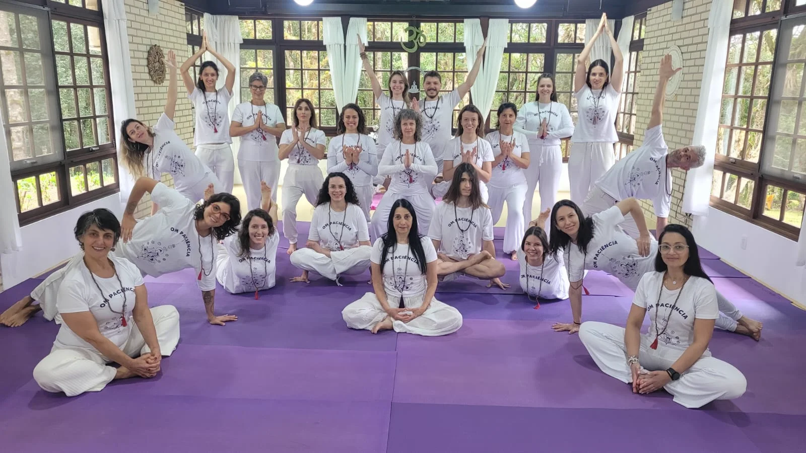 Turma formada em formação criativa com uniformes brancos no salão com colchonetes lilases