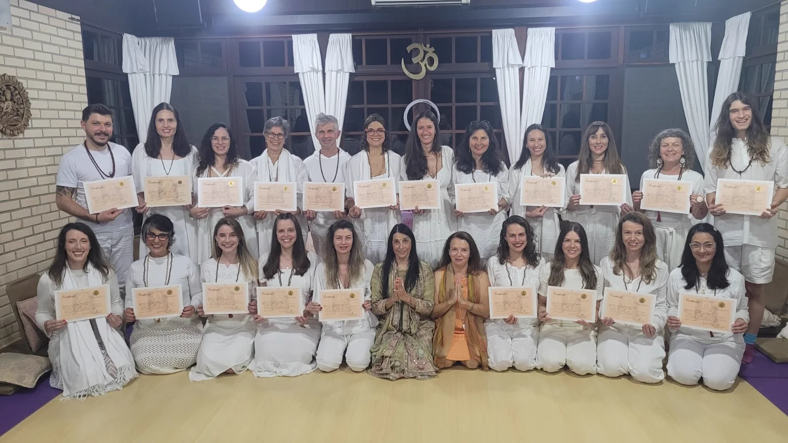 Formandos segurando certificados ao lado dos professores no Chacarānanda Ashram