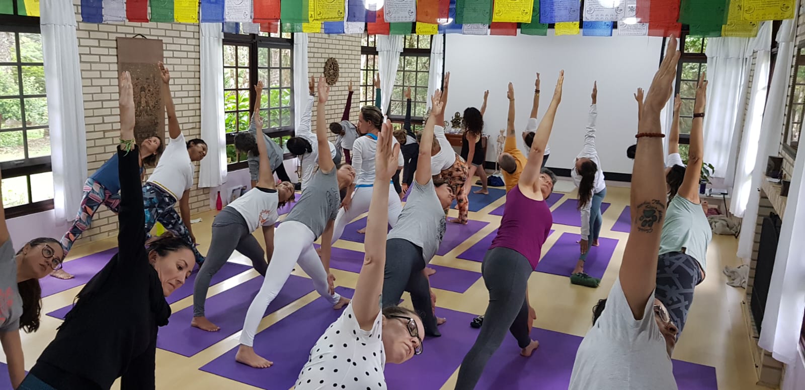 Aula prática de Yoga no salão com colchonetes lilases